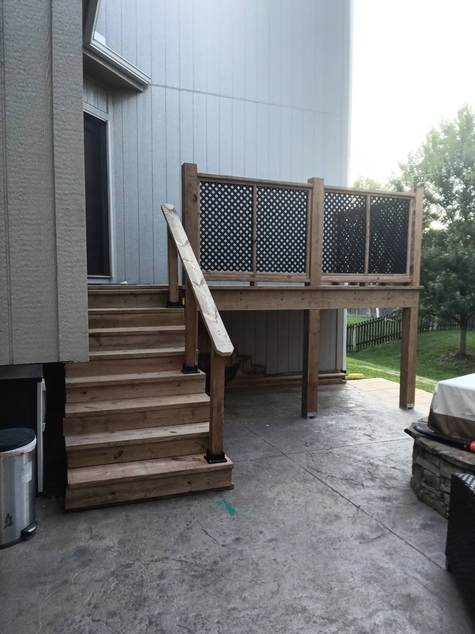 Completed elevated deck with stairs, support posts, and lattice privacy railing