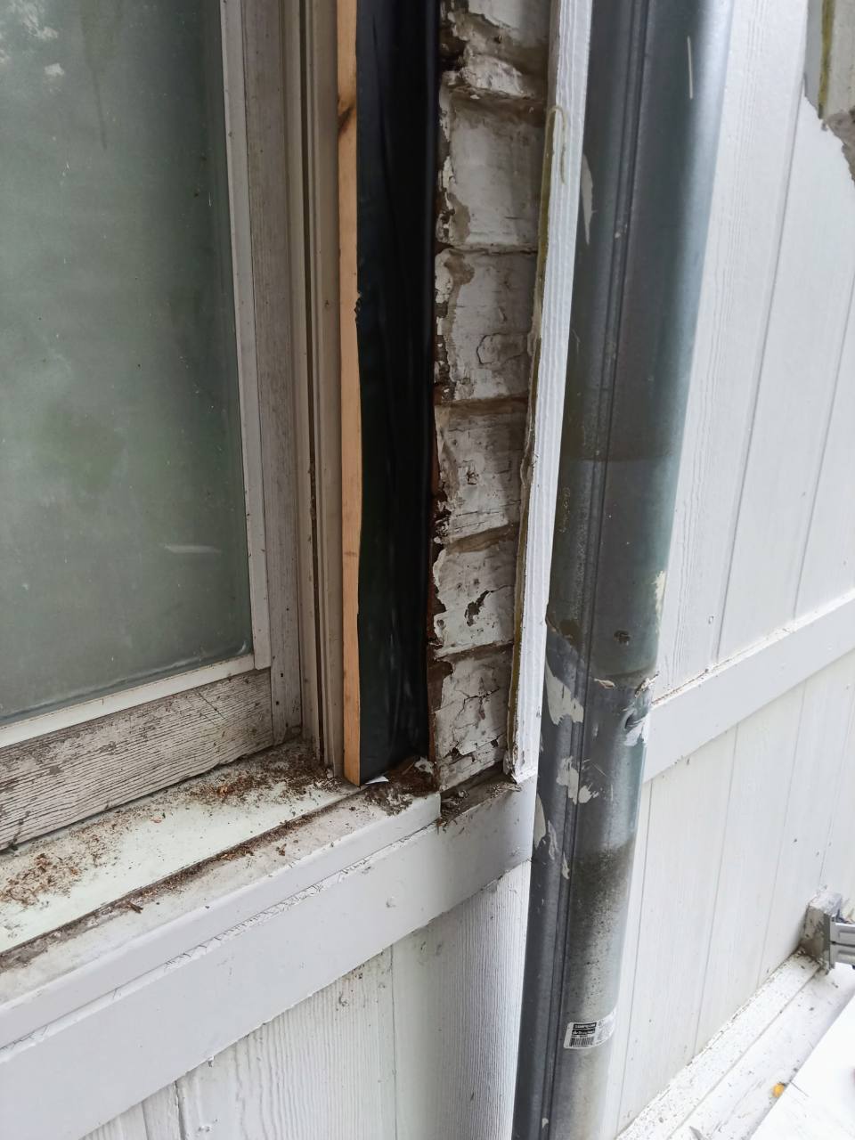 Close view of right-side window weatherproofing beside the downspout