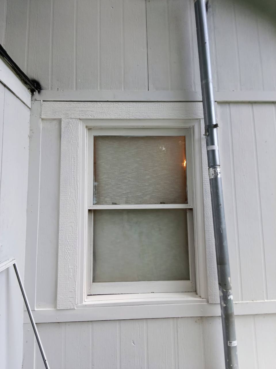 Completed exterior window repair with finished white trim and painted siding